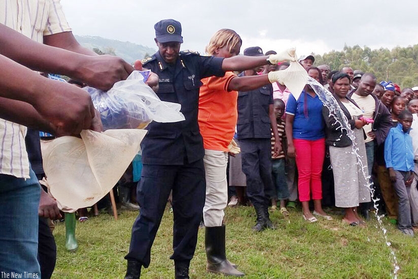 ACP Butare and Uwimana pour illicit gin during the public destruction exercise on Saturday in Gakenke District. / Courtesy.