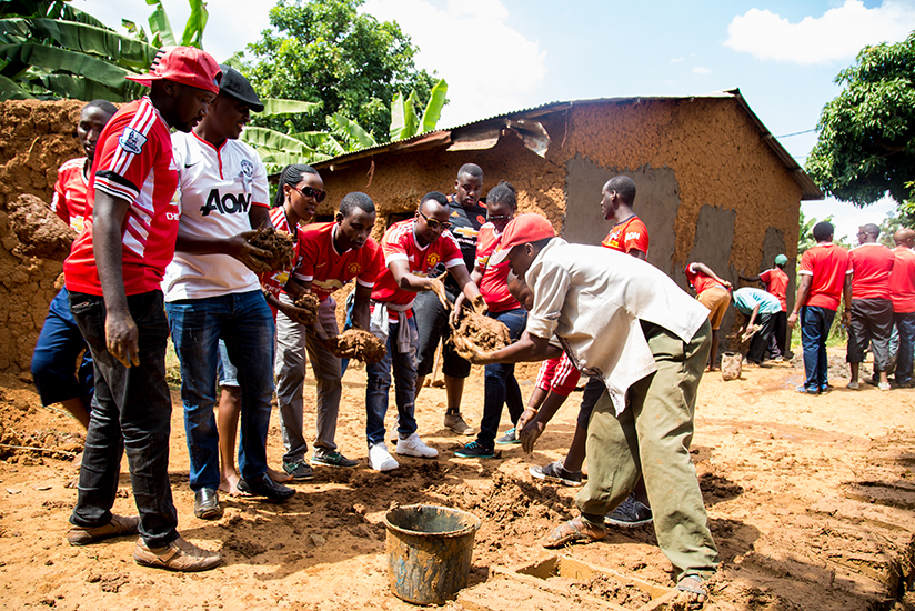 Members of the Manchester United fan club make bricks while others start works on the house (background) back in May. / Faustin Niyigena