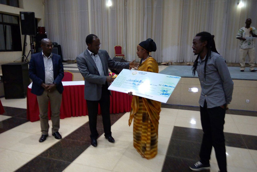 Ndayisaba hands over a cheque to Uwineza who emerged third in the song category. / Frederic Byumvuhore