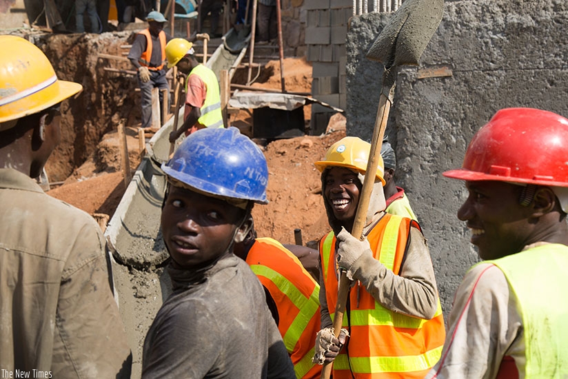 Masons at a construction site in Kigali share a light moment . (Timothy Kisambira.)