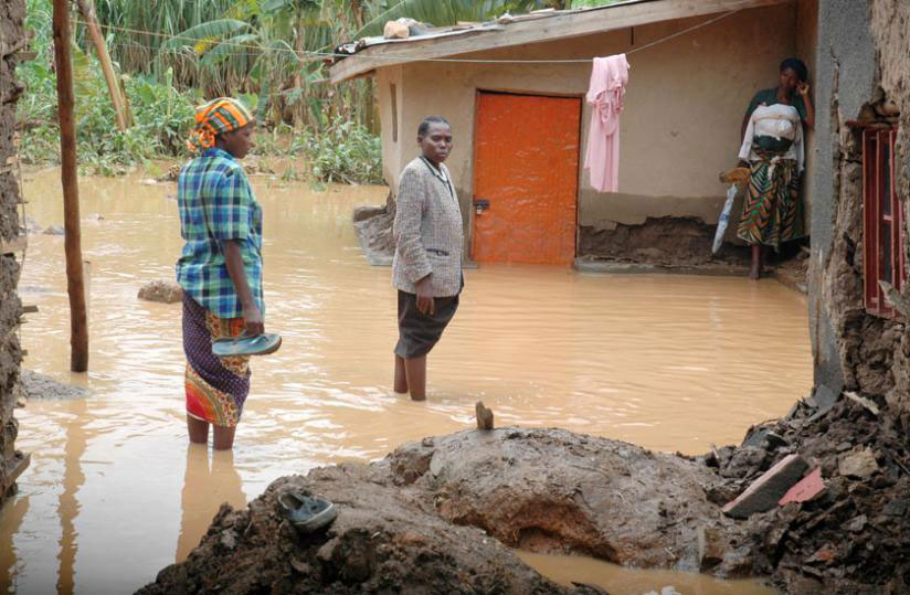 A family looks crestfallen after their home was submerged following heavy rain. Unpredictable weather patterns due to climate change are blamed for such disasters. / File