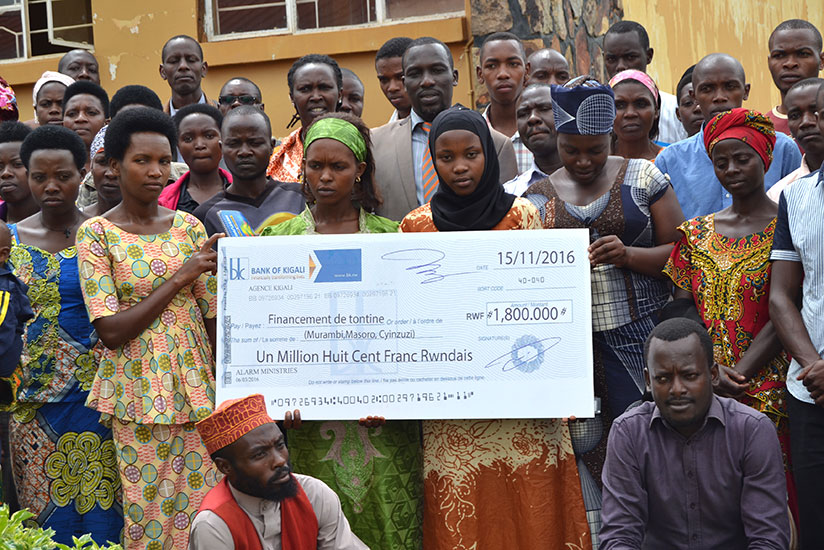 Some of the members of the women and youth savings groups pose with the dummy cheque of the donation. / Frederic Byumvuhore