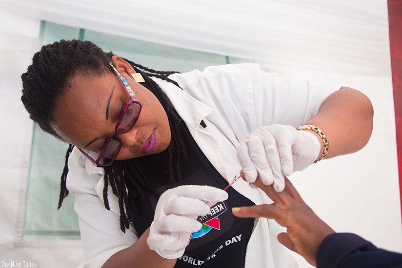 Nurse Julienne Nyiransabimana takes blood sample for an HIV test at Kigali Regional Stadium yesterday. (Faustin Niyigena)