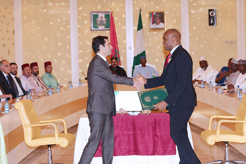 Elumelu and Benchaaboun exchange documents at the State House in Abuja during the official visit of His Majesty King Mohammed VI of Morocco to President Buhari. / Courtesy