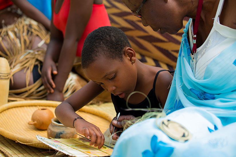 Vestine Mukamugema teaches 8-year-old Clarisse Kanyana from Kanombe how to make an art-craft piece during the National Children's Summit at Petite Stade in Remera yesterday. Gender and Family Promotion minister Esperance Nyirasafari has urged parents to ensure that children live in family environment to learn the country's positive cultural values. / Timothy Kisambira