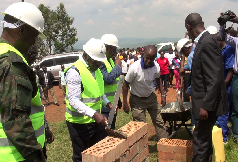 Minister Munyeshyaka (C) lays the foundation stone at Munini site where the model village will be constructed as Gasabo Mayor Lwamurangwa (R) looks on. (Photos by Eddie Nsabimana)
