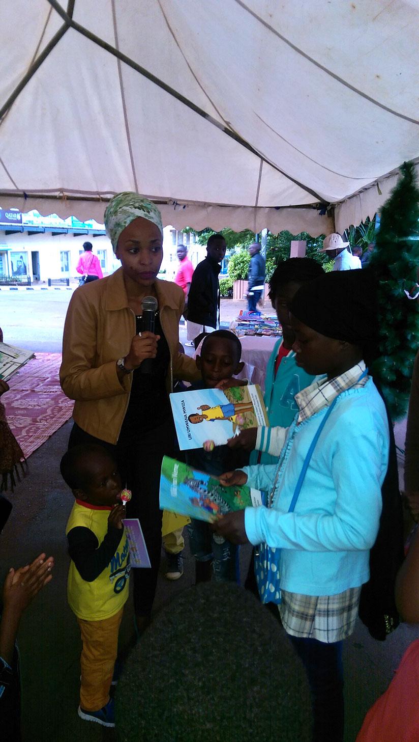 Najma Uwamahoro, the coordinator of Ikirezi Project, guides children at the Christmas book fair. / Dennis Agaba