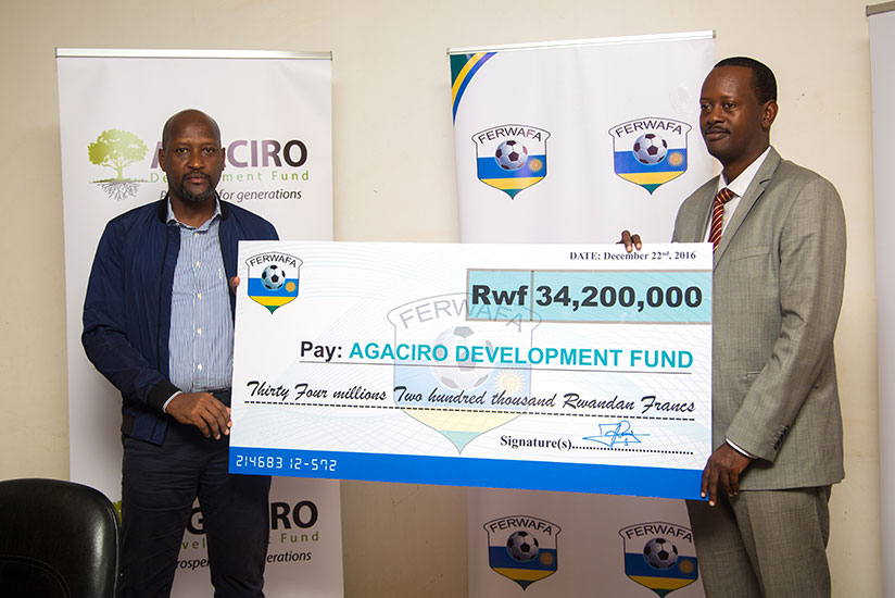 Nzamwita hands over a dummy cheque to Kayonga at Ferwafa offices in Remera, yesterday. / Faustin Niyigena