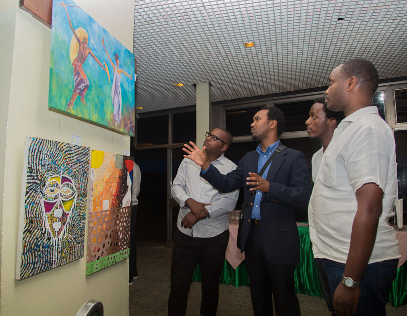 Gaby (centre) explains his paintings during the exhibition at Umubano Hotel, Kigali. / File