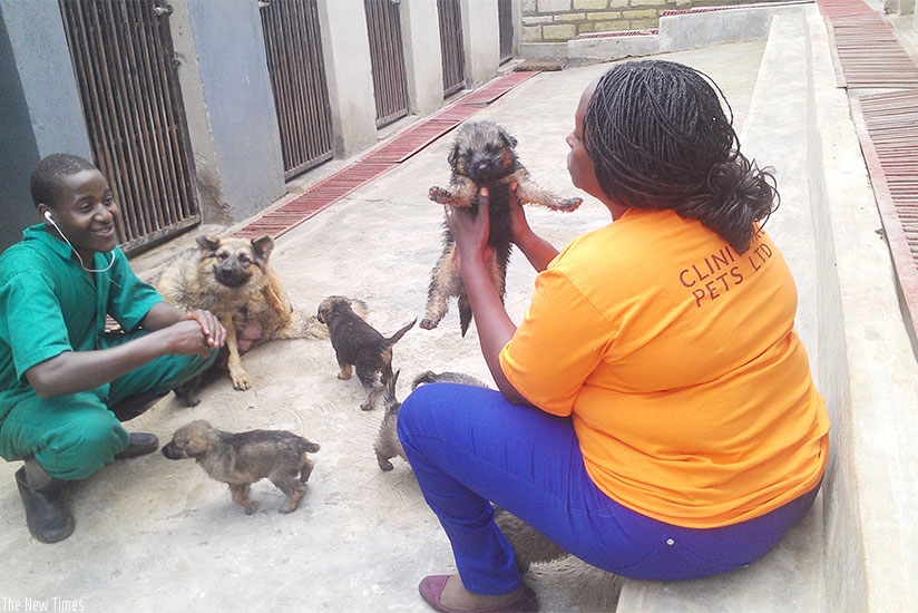Bigirimana plays with a puppy while one of the caretakers looks on. (All photos by Frederic Byumvuhore)