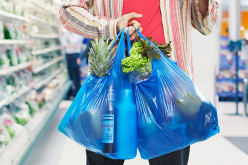 A shopper carries items in polythene bags .  (Net photo)