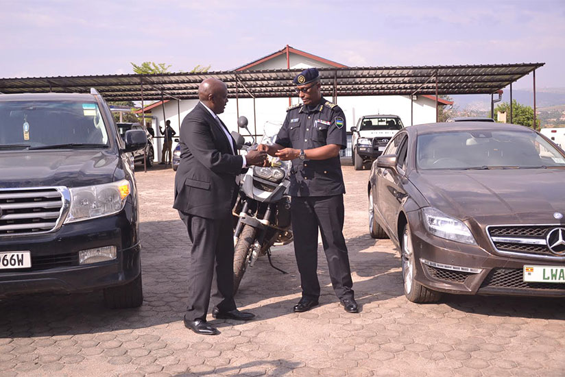 CP Emmanuel Butera handing over particulars of the handed over automobiles to Uganda's High Commissioner to Rwanda, Richard Kabonero.