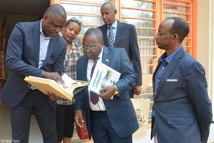L-R . PSF chairman Benjamin Gasamagera shows the Amb. Biang a profile of local investors yesterday. (T. Kisambira)