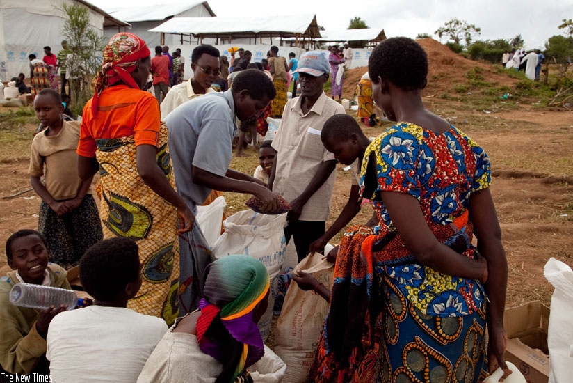 Burundian refugees receive food from World Food Programme officials in Mahama camp. The Ministry of Disaster Management and Refugees Affairs has urged refugees to start income gene....