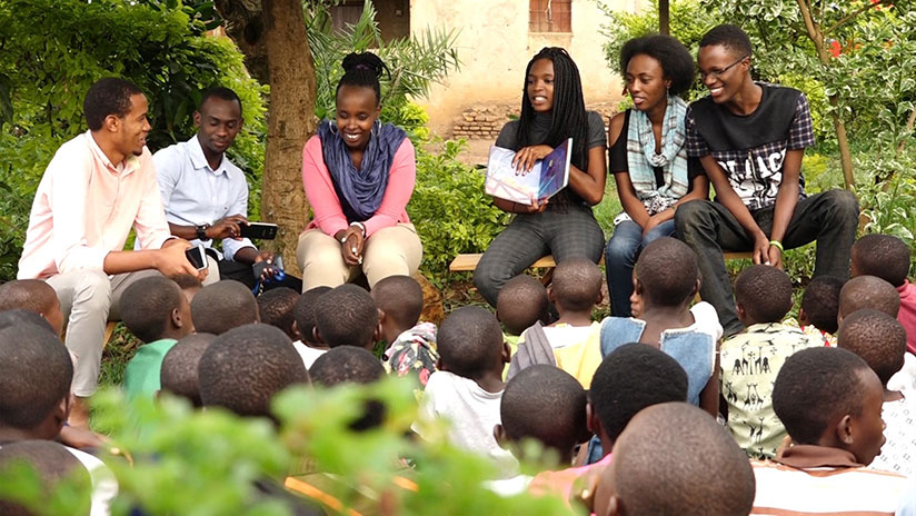 Dominique Uwase Alonga (centre right) reads a story to children at Ellie's Corner - a partner organization of Imagine We in Kigali. Courtesy.