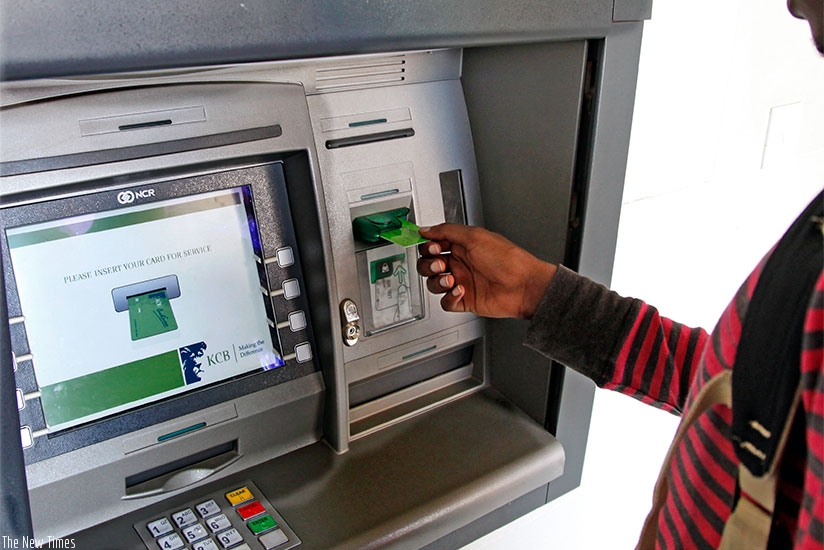 A bank client uses an automated card (Photo by T. Kisambira