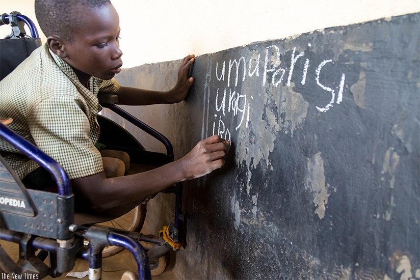 A child with disability writes on a blackboard at GS Bumbogo in Gasabo during a lesson. (Timothy Kisambira)