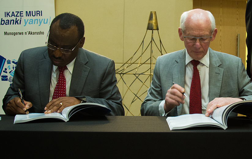 I&M Board Chairman Bill Irwin (right) signs IPO documents with Finance Minister Claver Gatete on Tuesday (Timothy Kisambira)