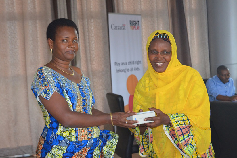 The mayor of Nyarugenge Kayisime Nzaramba hands over one of the smartphones to a teacher. / Hudson Kuteesa