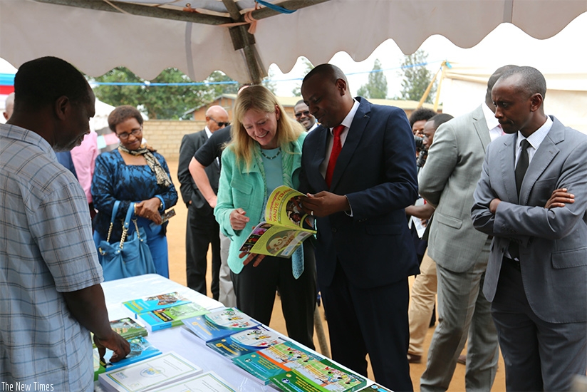 Centre, Munyakazi and Amb. Barks-Ruggles skim through one of Kinyawanda books that will be used in promoting Kinyarwanda among children. Courtesy.