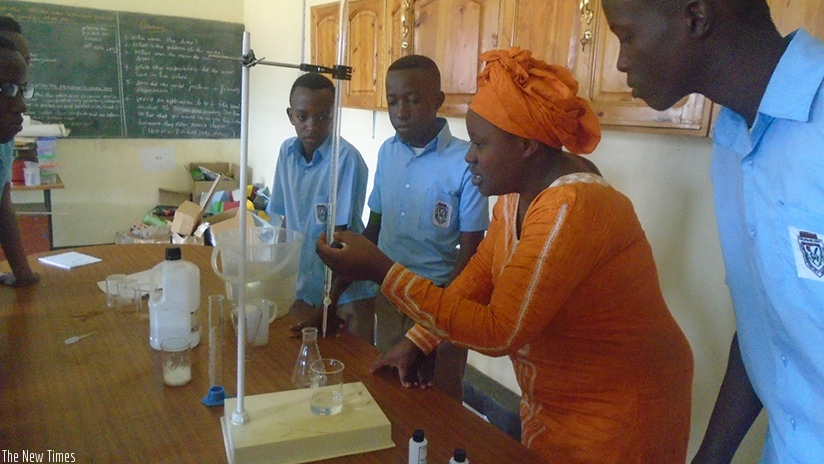 A teacher at Apaper Complex School helps students carry out  an experiment. / Lydia Atieno. 