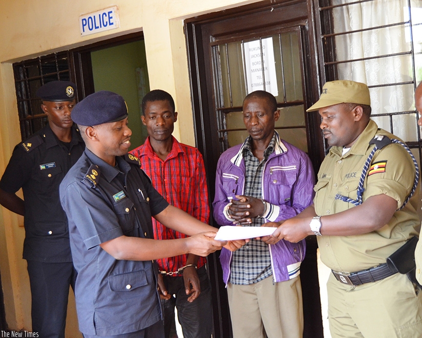 Senior Supt. Eric Kanyabuganza receiving deportation papers from Uganda Police Force as the deportees look on 