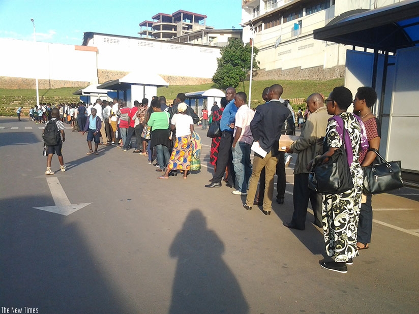 Passengers queue as they wait for buses at the taxi park in downtown Kigali. Ange Violette Iradukunda.