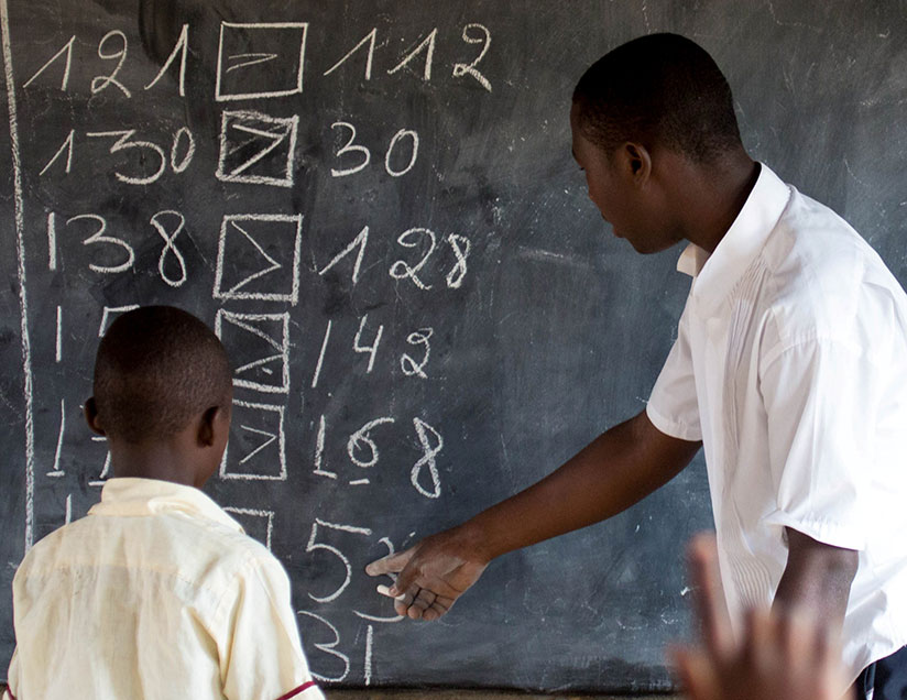 A teacher helps a pupil during class. Timothy Kisambira.