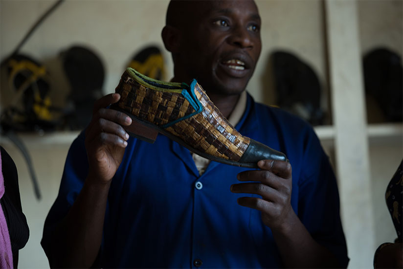 Hakizayezu displays one of the types of shoes he makes at Nyagatare-based factory. The businessman started off as a street shoe shine boy over 10 years ago. Below, a staffer puts f....