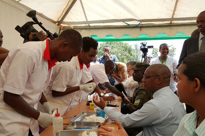 The State Minister for Public Health and Primary Healthcare, Dr Patrick Ndimubanzi (R), and other officials undergo health check-up from the newly-graduated healthcare practitioner....