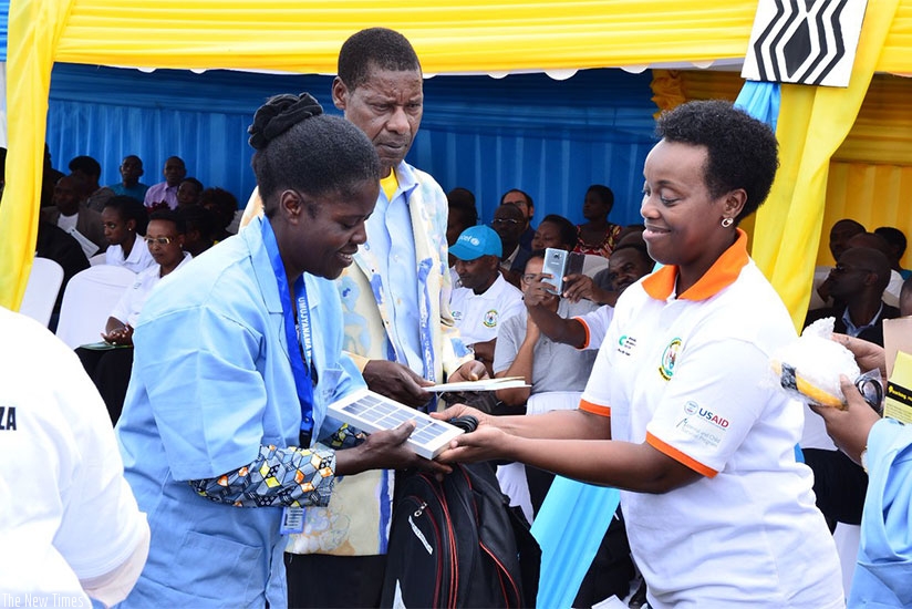 Dr Gashumba (R) hands over uniforms, badges and tool kits to community health workers to help them in their work. Hudson Kuteesa.
