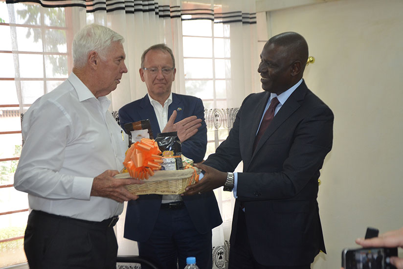 Gen. Michael Jeffery receiving some Rwanda products traded at international market from PSF Chairman Benjamin Gasamagera as Michael Roux the Honorary Consul General of Rwanda to Au....