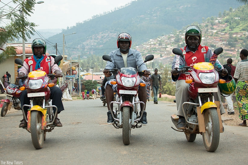 Tubanambazi (middle) and colleagues at work. The S6 dropout owns three moto taxis and is also the head of a motorcyclists group. / T.Kisambira.