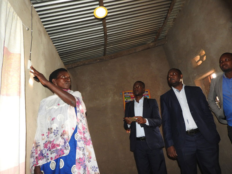 Murekatete tests her newly-acquired solar system as EDCL chief Emmanuel Kamanzi and Ignite official watch. / Kelly Rwamapera