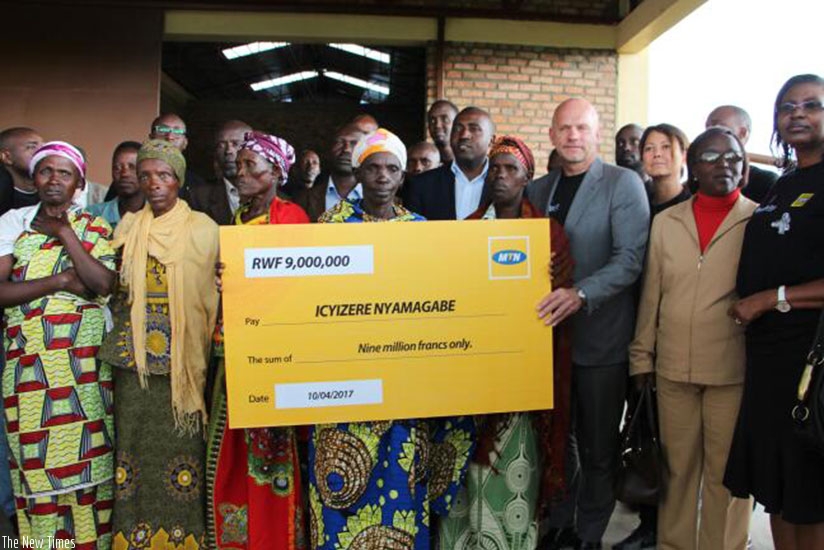 MTN CEO Bart Hofker (3rd right) hands over a dummy cheque for the donation on Monday. The money will benefit survivors in Maryohe village.  (Photos by Eddie Nsabimana)