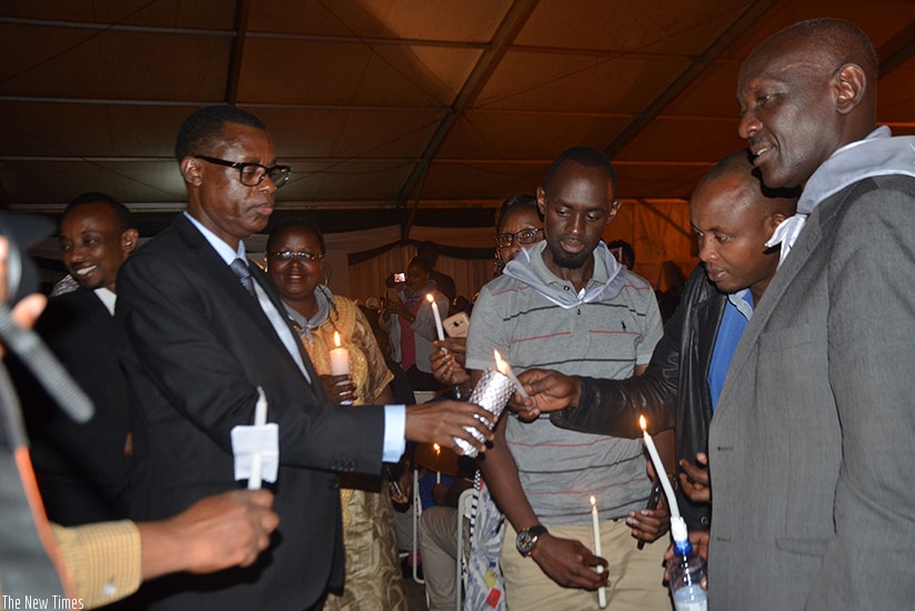 Minister Kabarebe (L) helps mourners light candles  in honour of  Genocide victims at Gikondo on Thursday. Courtesy. 