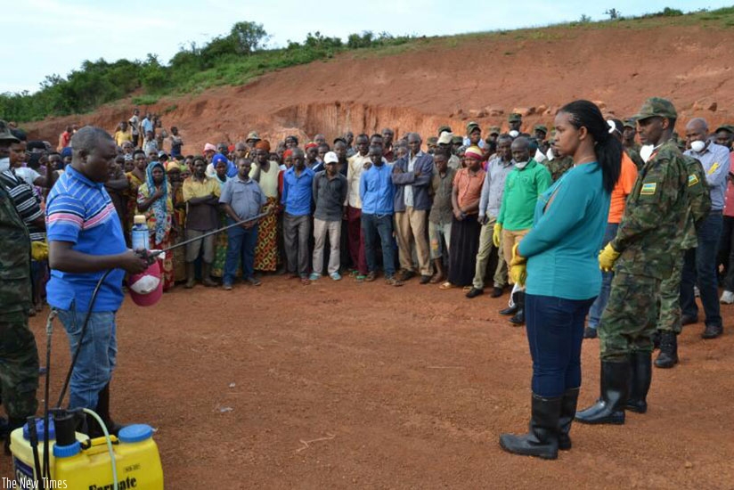 Kazayire (R) and farmers in Nasho in Kirehe District being shown how to use the pesticide. (Photos by K. Rwamapera)