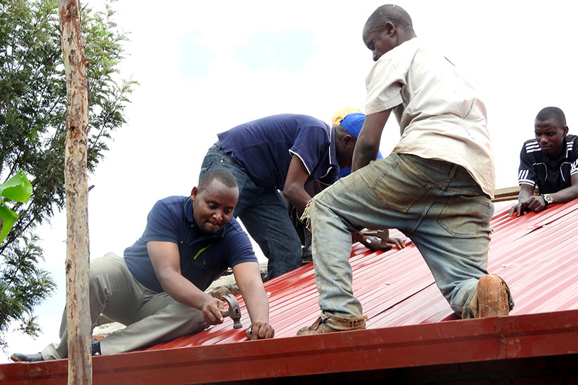 Rwambara (L) helps to roof a house for a Genocide survivor in Kirehe. / John Mbaranga