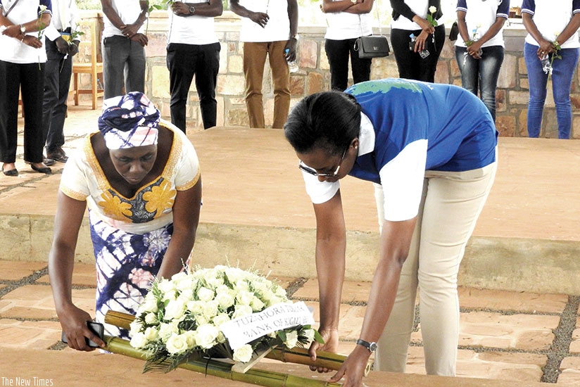 Dr Karusisi (R) and Uwiragiye lay a wreath on a grave at Ntarama memorial. Elias Hakizimana.