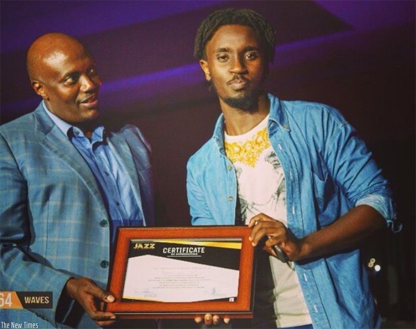 Sadu Vybz (R) receives a certificate, in honour of his outstanding graphic design work, from former Ugandan High Commissioner to Rwanda, Richard Kabonero.