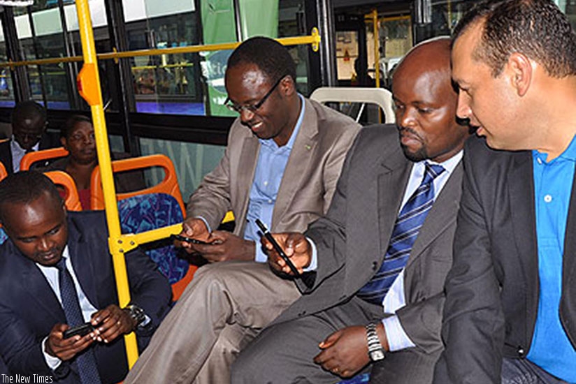 Youth and ICT minister Jean Philbert Nsengimana and other government officials try out a wireless internet connection in a city bus. (File)