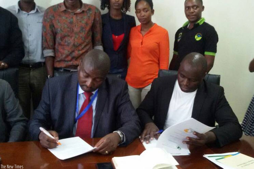 Hategekimana (L) and Ariho sign the agreement in Kigali yesterday. (Elias Hakizimana)