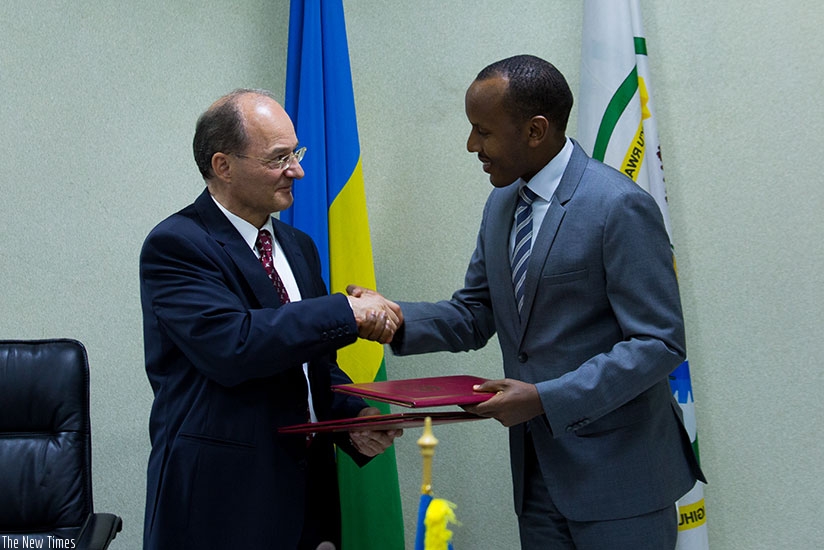 Gies (L) exchanges documents with Caleb Rwamuganza, the permanent secretary at the Ministry of Finance. (Photos by Timothy Kisambira)
