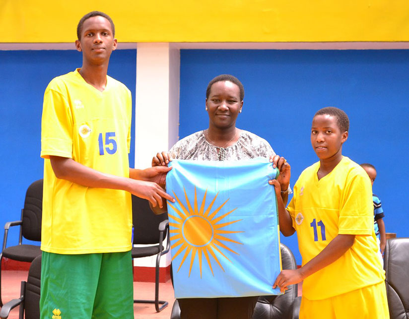 Minister Uwacu hands over the national flag to the captains of both teams at Amahoro Indoor Stadium on Sunday. / Courtesy