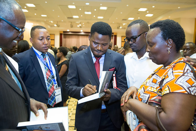 MP Bamporiki signs books ahead of the launch of 'My Son, It Is A Long Story' in Kigali on Sunday. (Courtesy photos)