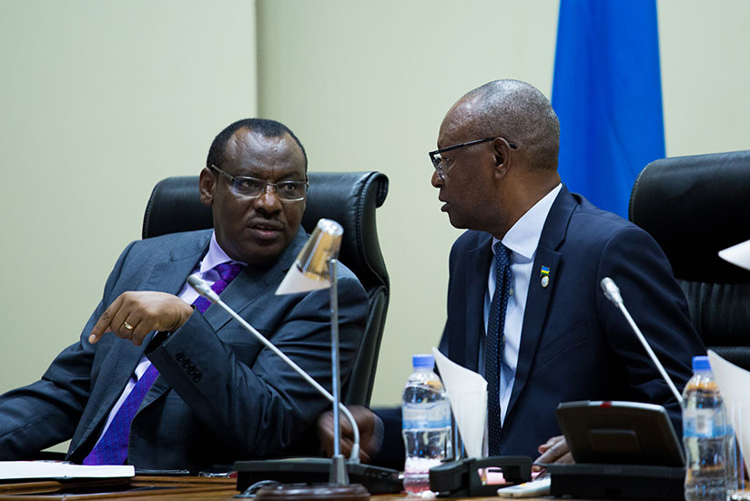 Finance and Economic Planning minister Claver Gatete (L) consults with MP Adolphe Bazatoha at Parliament yesterday. The minister said the Government will soon set up a long-term National Public Savings Scheme to help majority of the country's population working in the informal sector save for future investments and retirement. / Timothy Kisambira