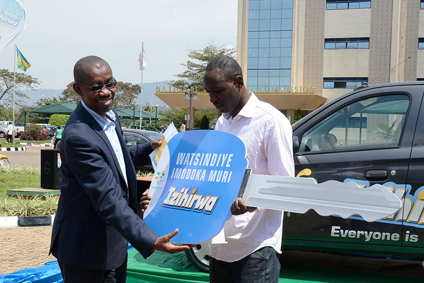 Pascal Ruganintwari, deputy commissioner general at RRA, hands over a dummy key for the car to Aaron Uwimana. / Appolonia Uwanziga