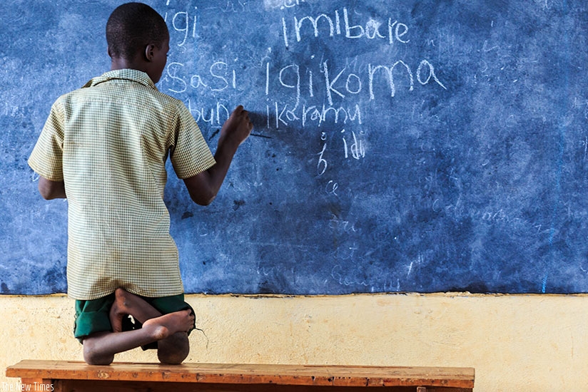 A physically handicapped learner writes on a blackboard during a lesson at a school in Bumbogo Sector, Gasabo District. Timothy Kisambira.