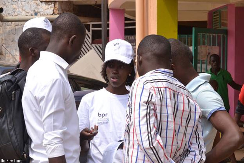 A BPR employee (middle) sensitising Kigali residents about saving. 