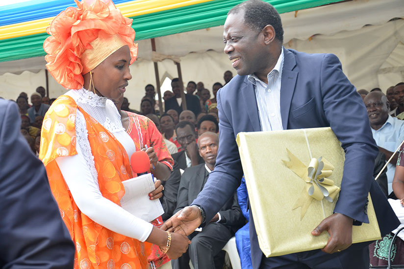 State Minister Fulgence Nsengiyumva shakes hand with Aisha Umurerwa, CO-DERVAM's accountant, after receiving a present. / Kelly Rwamapera